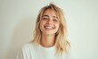 © Valentyna - A cheerful young woman with blonde hair, wearing a white T-shirt, smiling and standing against a plain white background