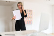 © Guille Faingold/Stocksy - Businesswoman reviewing documents while on a call