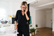 © Guille Faingold/Stocksy - Woman working in a modern kitchen while on a call