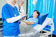 © NanSan - Two Muslim female doctors check the medical history and symptoms of a male patient lying in bed after surgery at the hospital, monitoring his recovery and health status