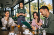 © Mediteraneo - Group of people ordering food from the waitress. Waitress writing orders down on tablet. Undecided people reading the menu while the waitress waits and helps them.