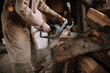 © Cavan Images - Old man cutting firewood with a chainsaw. Sawdust flying everywh