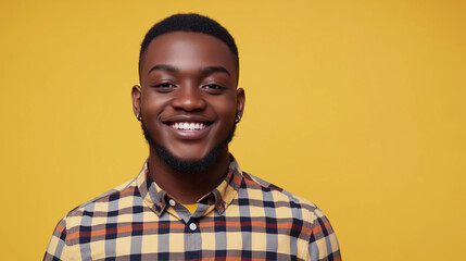 Happy African American man in checkered shirt standing alone in front of yellow background