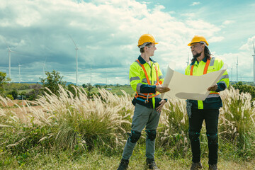 Engineer team mix black and white male workers with floor plan at Wind Turbines field working survey at wind electricity generator farm field outdoor.