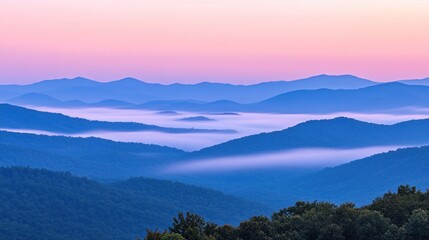 A breathtaking panoramic view of a mountain range with fog rolling through the valleys, bathed in a soft pink and blue sunrise light.