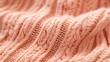 © Kadri - Close-up of the texture and pattern on a peach-colored sweater, highlighting its soft fabric with subtle cable-knit detailing