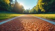© AGUNG - Red running track with white lines, green grass, trees, and a bright sun in the background.