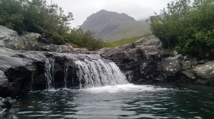 Waterfall in the Fairy Pools, Glen Brittle, Isle of Skye, Scotland, UK. On a gray day in the fall you see the water flowing along the rocks with in the background the famous mountain with the crack in