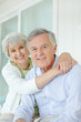 © peopleimages.com - Hug, love and smile of mature couple on sofa in living room of home together for bonding or commitment. Face, retirement or portrait of senior man and woman embracing in apartment for safety or trust