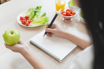 Wellbeing of health with good food control concept. Woman writing the meal note and plan to eat during diet program to loss weight goal for balance nutrition and calories.