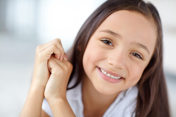 Happy, confident or portrait of girl in home for joy, growth and fun in living room of house to relax. Smile, young or face of healthy female kid alone for playing, satisfaction or childhood in Spain