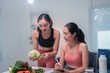 © Tj - Asian nutritionist holding cauliflower and explaining healthy eating habits to her client, who is taking notes on a clipboard, during a consultation at home