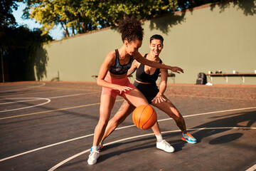 Wall Mural - Fun, basketball and women playing game together for competition, challenge and fitness on playground. Outdoor, performance and girl friends on court with ball, exercise and teamwork at sports club.