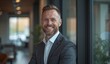 © Yury - Confident businessman smiling warmly in modern office setting