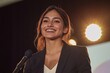 © Maelgoa - A young Hispanic businesswoman wearing a professional suit, beaming with pride while accepting an award on stage, spotlight on her confident smile, medium close-up of her hands 3