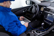 © zphoto83 - A technician performs diagnostics on a car using a laptop while seated inside the vehicle at an automotive service center