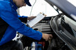 © zphoto83 - Automotive technician performing an inspection under the hood at a repair shop during daytime