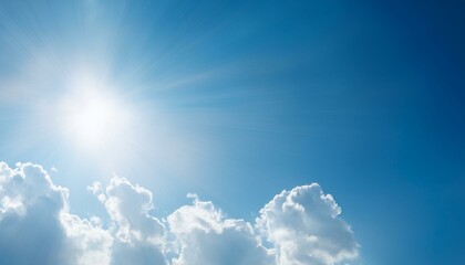 a bright sun shines through fluffy white clouds in a clear blue sky.