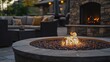 © vefimov - The image depicts a cozy outdoor lounging area featuring a wood-burning fire pit as the centerpiece, surrounded by comfortable patio furniture in an inviting residential setting.