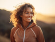 © PulseImages - Smiling Woman with Curly Hair in Jacket Outdoors at Sunset, Ideal for Adventure, Fitness, and Lifestyle Themes