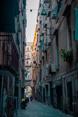 Typical streets in Napoli downtown or old city. Narrow streets with high buildings, clothes hanging on lines and drying bwtween the buildings. Moto scooters everywhere