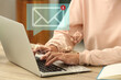 © New Africa - Woman using laptop at table, closeup. Envelopes as symbol of message over computer