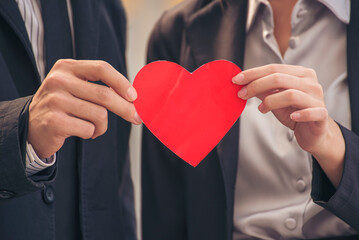 Couple lover in love smile and looking eyes each other with happiness romantic relationship. Couple lover holding red heart shape symbol of love. Close up face shot love at first sight flirting date