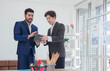 © Singh - Business man asian two person wearing a black suit handsome standing looking success committed hand holding mobile phone and laptop ready for work marketing in room office, with white background