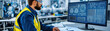 © Enjoy - focused engineer in safety vest analyzes technical blueprints on dual monitors in modern industrial workspace, showcasing precision and innovation