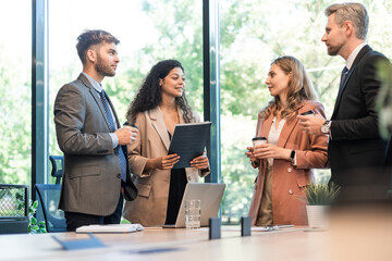 Poster - Group of a professional business team standing and discussing in modern bright office.