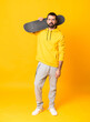 © luismolinero - Full-length shot of man over isolated yellow background with a skate