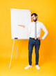 © luismolinero - Full-length shot of businessman giving a presentation on white board over isolated yellow background holding copyspace with doubts