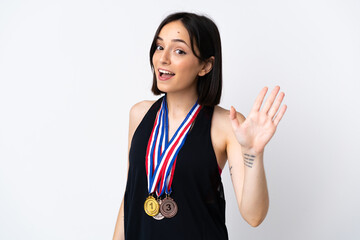 Young woman with medals isolated on white background saluting with hand with happy expression