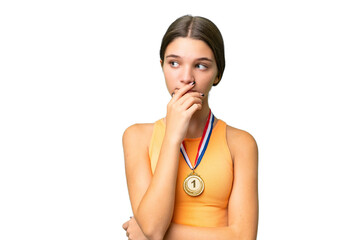 Wall Mural - Teenager caucasian girl with medals over isolated background having doubts and with confuse face expression