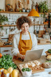 © VERTEX SPACE - A woman in cozy kitchen, wearing an apron, smiles while using laptop surrounded by fresh vegetables and herbs. warm atmosphere enhances her joyful expression