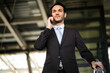 © Minerva Studio - Confident businessman in a suit talks on his cell phone while strolling through a modern cityscape