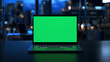 © Tatiana - A modern laptop displays a bright green screen against a city skyline at night, highlighting the potential for digital creativity