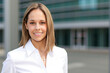 © Minerva Studio - Young businesswoman smiling in front of office building