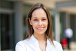© Minerva Studio - Portrait of smiling young businesswoman standing outside office building