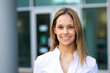 © Minerva Studio - Smiling businesswoman standing outside office building