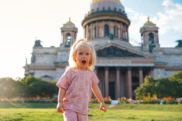 Wall Mural - Cute little child girl travels with her family in the summer at St. Isaac's Cathedral in St. Petersburg, active childhood.