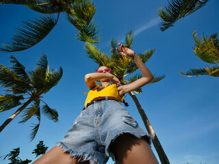 Woman enjoys the sunny day posing casually among palm trees in her casual attire