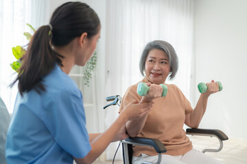friendly caregiver helping senior woman with dumbbell exercise at home, supporting health, wellness,