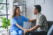 © amnaj - Young nurse holding senior patient's hands, comforting him during a home visit, providing medical and emotional support