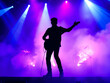 © Vectplus - Silhouette of a man playing guitar on stage, surrounded by swirling smoke, creating a dramatic and artistic atmosphere