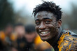 © Gonzalo - A joyful rugby player with a big smile slides through a field covered in mud. The image captures the fun and exhilaration of playing sports in tough conditions