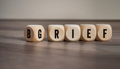 cubes, dice or blocks with brief and grief on wooden background