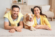 © Pixel-Shot - Young couple with Australian Shepherd dog lying on floor at home