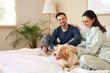 © Pixel-Shot - Young couple with Australian Shepherd dog sitting in bedroom