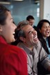 © vefimov - A man and women in a meeting laugh, enjoying workplace humor.